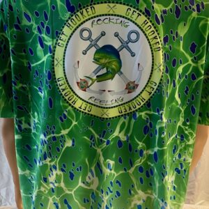 Green patterned shirt with a circular logo featuring a frog and scissors.